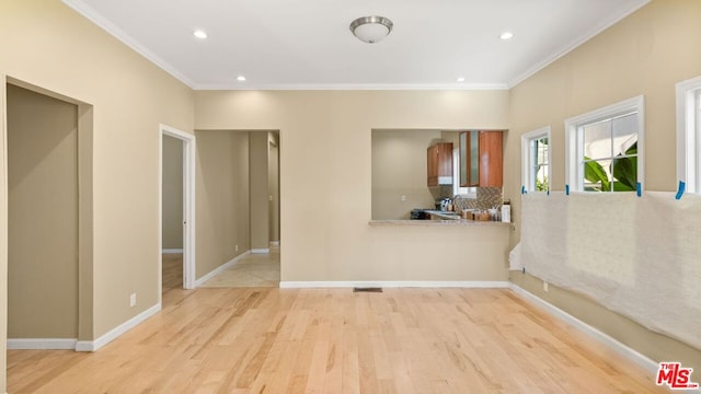 spare room featuring ornamental molding and light hardwood / wood-style floors