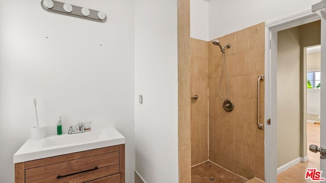 bathroom featuring tiled shower, vanity, and hardwood / wood-style flooring