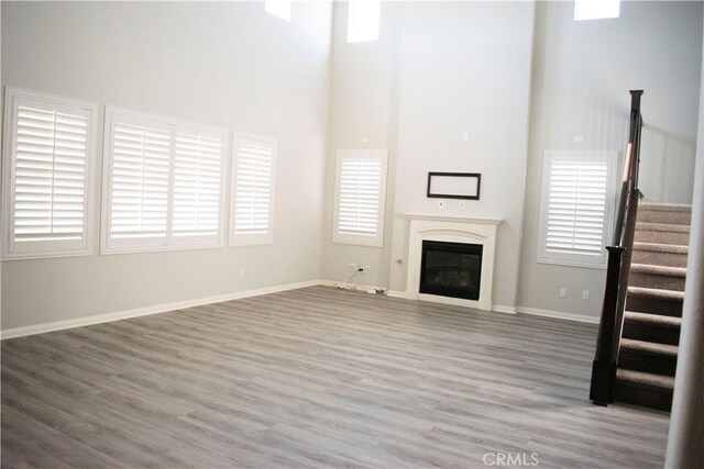 unfurnished living room featuring a towering ceiling and hardwood / wood-style flooring