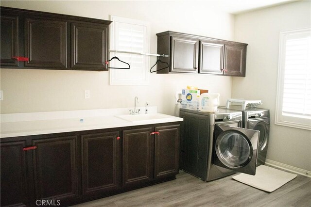 laundry room with cabinets, sink, light hardwood / wood-style flooring, and washing machine and dryer