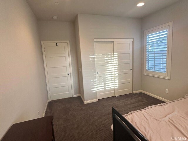 unfurnished bedroom with dark carpet and a closet