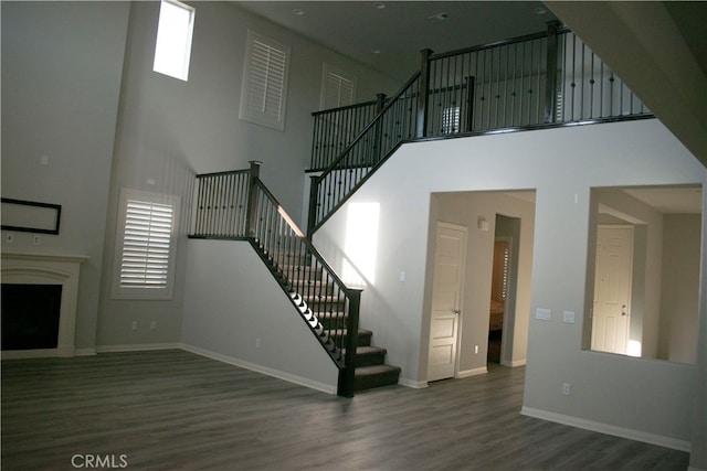 stairway with wood-type flooring and a high ceiling