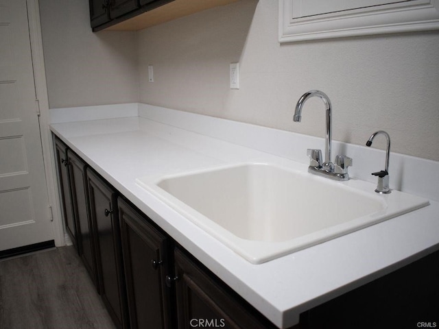 kitchen with dark brown cabinetry, sink, and dark wood-type flooring