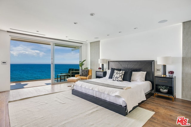 bedroom with access to outside, a water view, and dark wood-type flooring