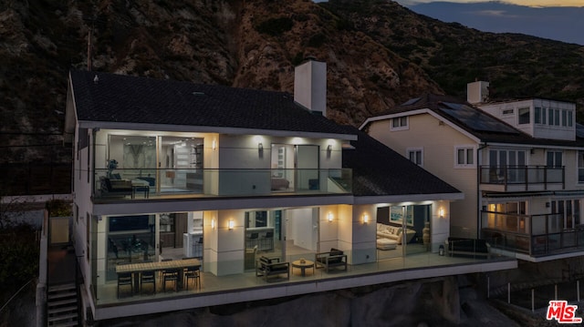 back house at dusk featuring a mountain view and a balcony