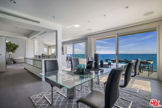 dining room with a water view, a raised ceiling, and sink