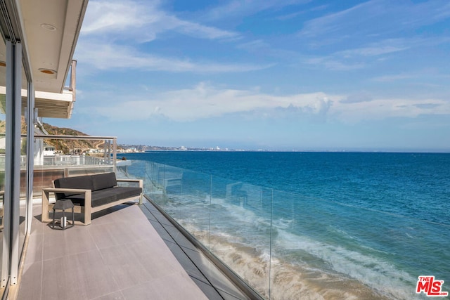 balcony featuring a view of the beach and a water view