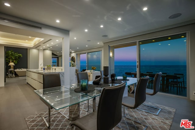 dining area with a water view and a tray ceiling