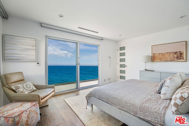 bedroom featuring access to exterior, a water view, and light hardwood / wood-style floors