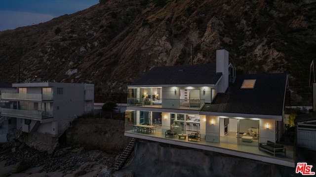 rear view of property featuring a mountain view and a balcony