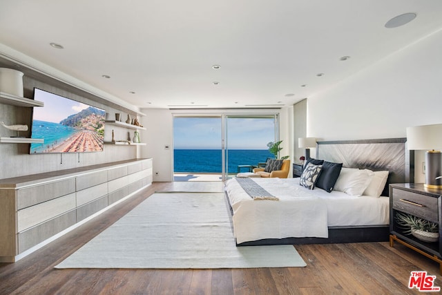 bedroom with dark hardwood / wood-style floors, a water view, access to outside, and multiple windows