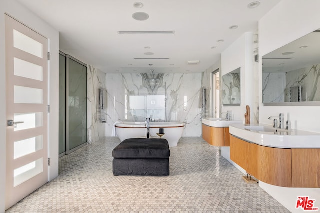 bathroom featuring walk in shower, vanity, and tile walls