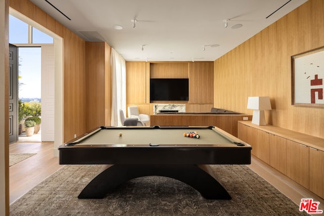 game room featuring light wood-type flooring, pool table, and wood walls