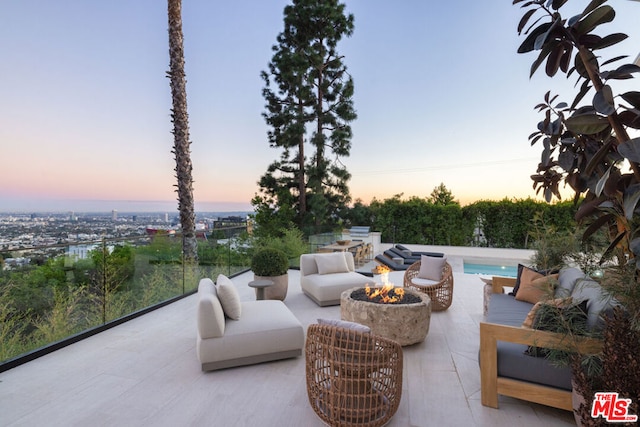 patio terrace at dusk with an outdoor living space with a fire pit