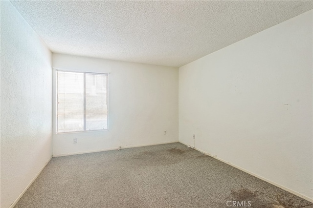 carpeted spare room with a textured ceiling