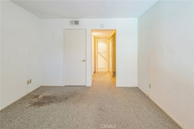 carpeted empty room with a textured ceiling