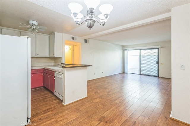 kitchen with white cabinets, ceiling fan with notable chandelier, white appliances, a textured ceiling, and hardwood / wood-style floors