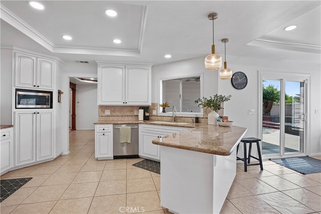 kitchen with white cabinets, appliances with stainless steel finishes, kitchen peninsula, and a tray ceiling