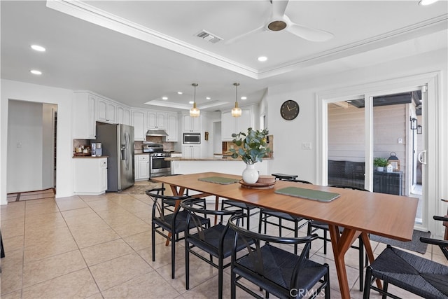 tiled dining area featuring ceiling fan, a raised ceiling, and crown molding