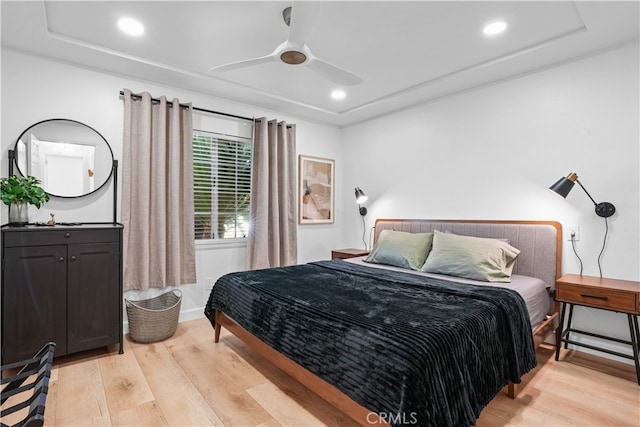 bedroom featuring light wood-type flooring, ceiling fan, and a raised ceiling