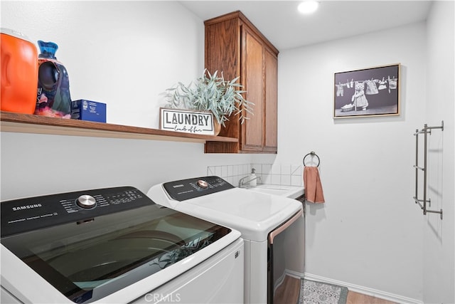 laundry room featuring washing machine and clothes dryer, cabinets, and sink