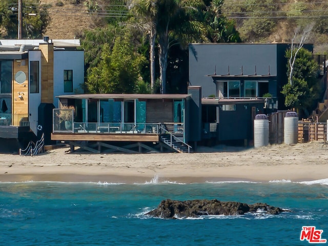 back of property featuring a water view and a beach view