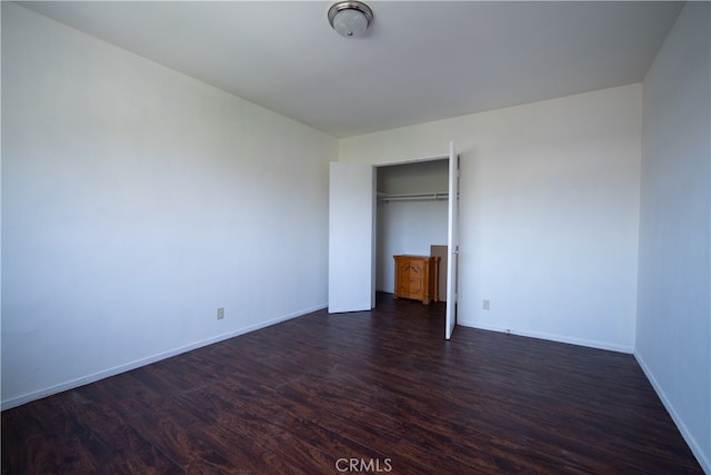 unfurnished bedroom with dark wood-type flooring and a closet