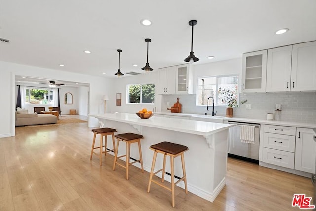 kitchen featuring stainless steel dishwasher, white cabinets, sink, and a wealth of natural light