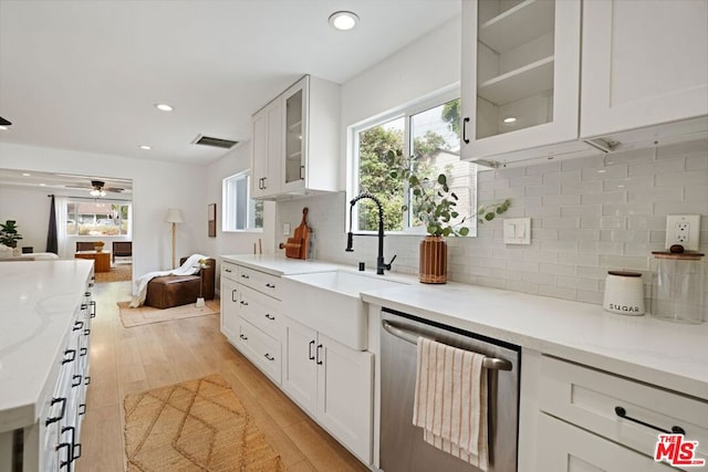 kitchen with light wood-type flooring, white cabinets, light stone counters, sink, and dishwasher