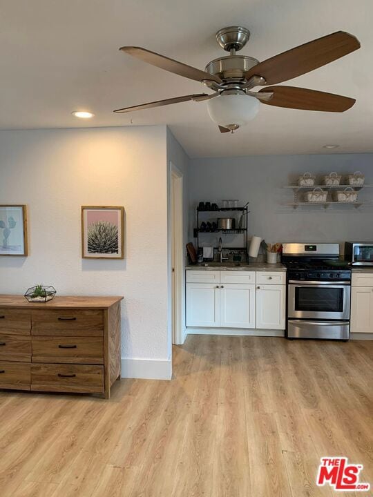 kitchen with white cabinetry, light hardwood / wood-style flooring, stainless steel appliances, and sink