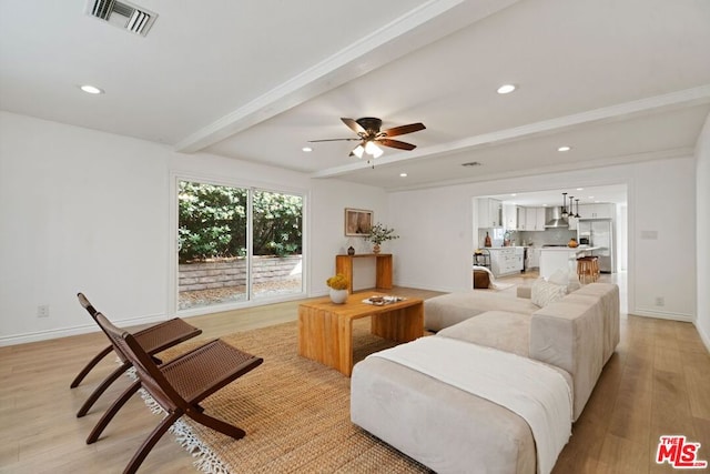 living room featuring ceiling fan, light hardwood / wood-style floors, and beam ceiling