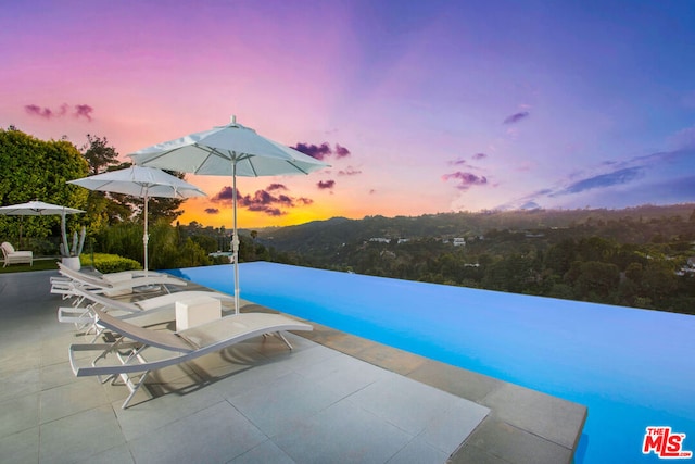 pool at dusk with a mountain view and a patio