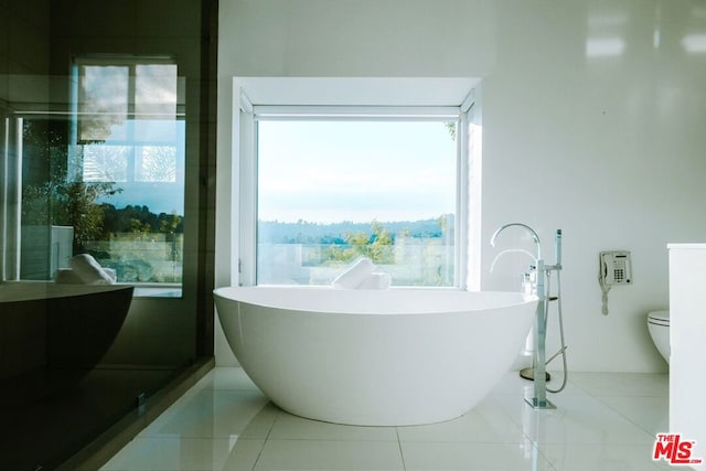 bathroom with tile patterned flooring, toilet, and a tub to relax in