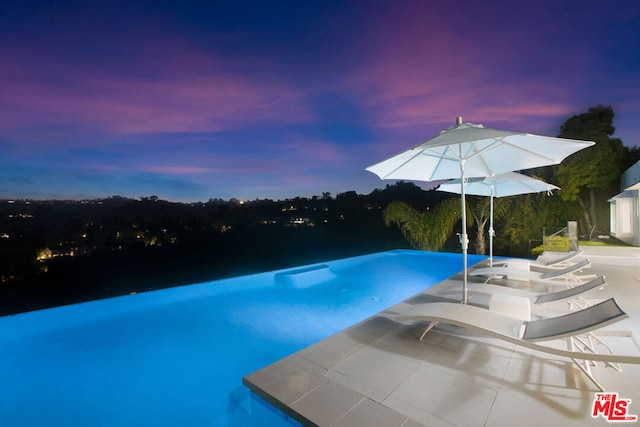 pool at dusk featuring a patio