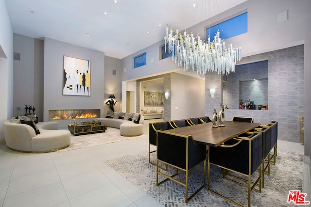 dining room featuring a high ceiling, light tile patterned flooring, a chandelier, and tile walls