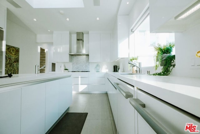 kitchen featuring white cabinetry, sink, wall chimney exhaust hood, decorative backsplash, and light tile patterned floors