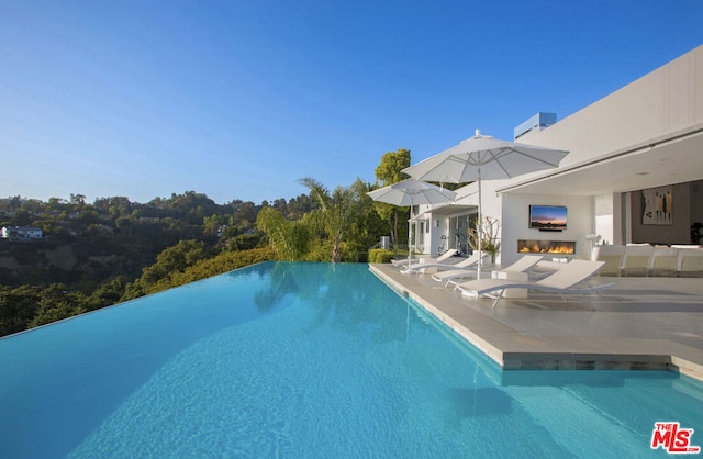 view of swimming pool with a patio area and an outdoor fireplace