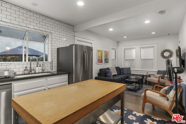 kitchen featuring appliances with stainless steel finishes, sink, backsplash, dark wood-type flooring, and beam ceiling