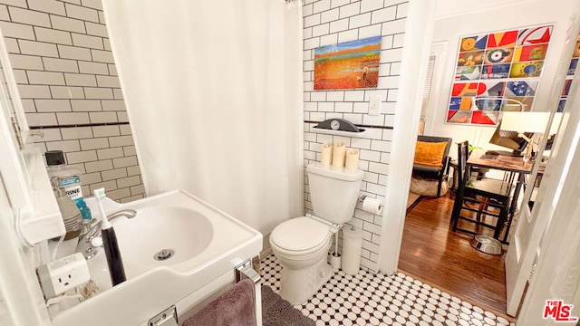 bathroom featuring toilet, sink, and tile walls