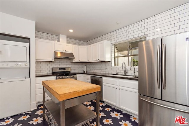 kitchen featuring stacked washer / dryer, white cabinetry, sink, decorative backsplash, and stainless steel appliances