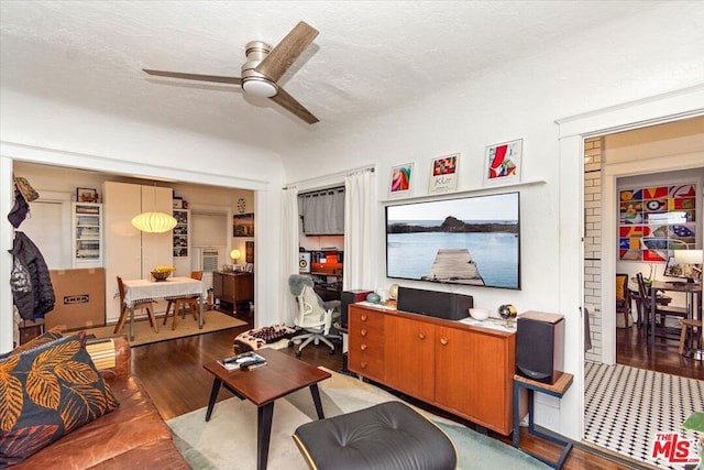 living room with ceiling fan, a textured ceiling, and light wood-type flooring