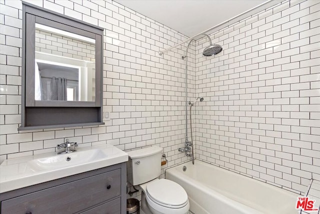 full bathroom featuring toilet, tile walls, vanity, tiled shower / bath combo, and backsplash