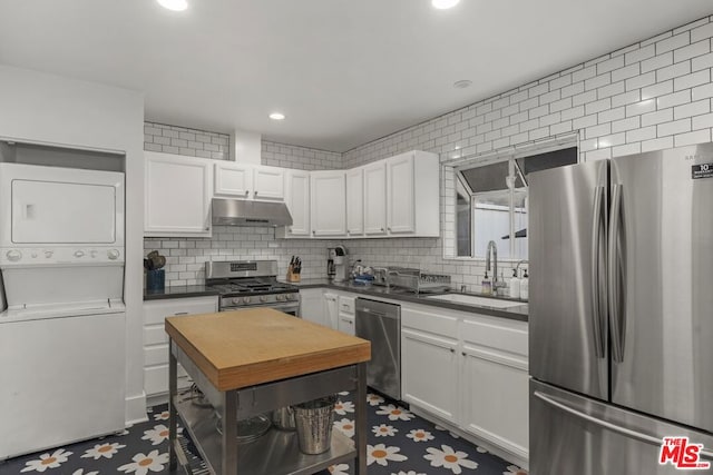 kitchen featuring sink, stainless steel appliances, white cabinets, and stacked washing maching and dryer