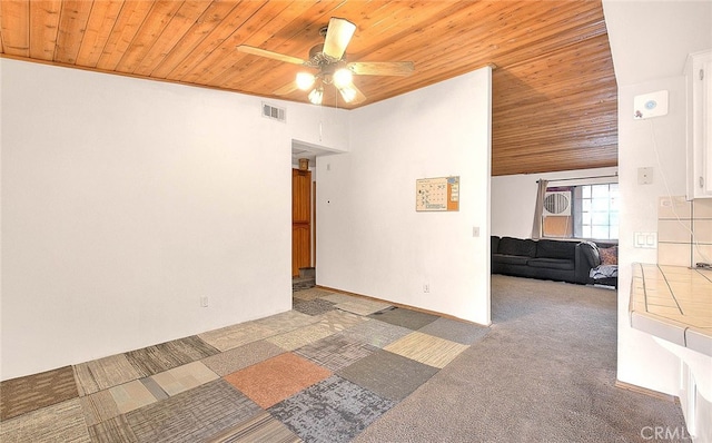 carpeted empty room featuring ceiling fan and wooden ceiling