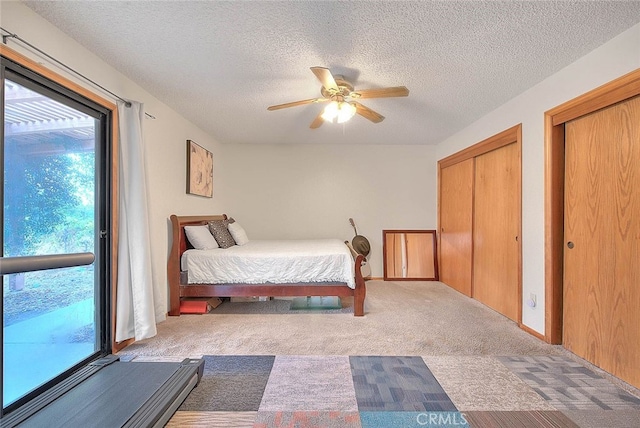 bedroom featuring ceiling fan, a textured ceiling, two closets, and light carpet