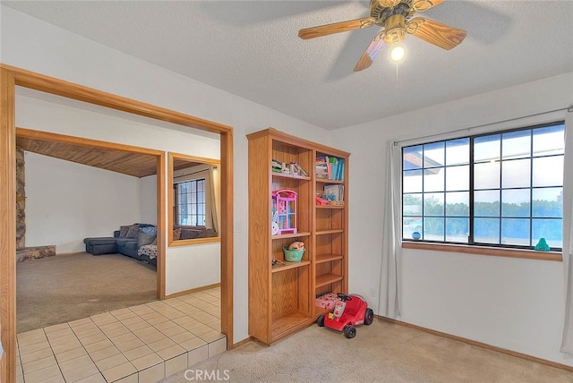 recreation room featuring light carpet, a textured ceiling, and ceiling fan