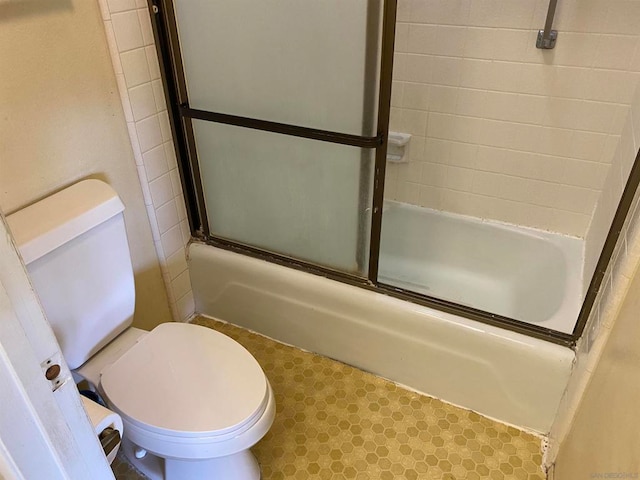 bathroom with toilet and combined bath / shower with glass door