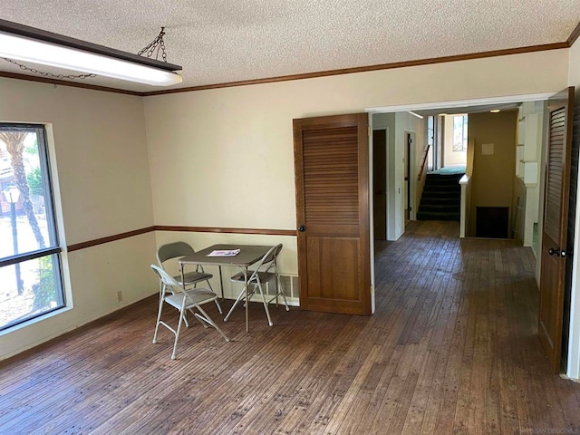 unfurnished dining area with a textured ceiling, crown molding, and dark hardwood / wood-style floors