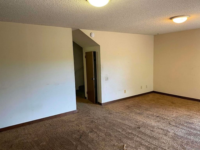 unfurnished room with a textured ceiling and dark colored carpet