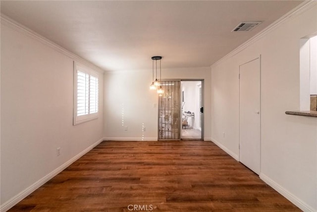 unfurnished dining area featuring dark wood-type flooring, crown molding, and a chandelier